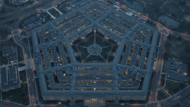 Aerial view of the Pentagon complex at dusk, illuminated windows and city lights