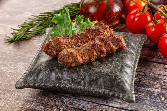 Grilled balkan cevapcici meat rolls with rosemary and cherry tomatoes