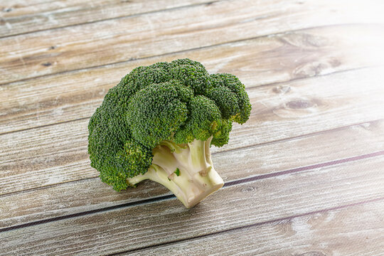 Single head of fresh broccoli on a light wood background with copy space