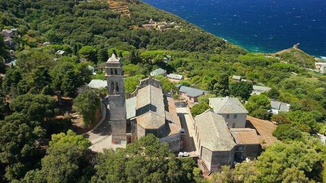 Pino Cap Corse Corsica 4K drone video. Descending fly down reveal of Santa Maria Assunta church and Saint Francois convent tower above blue sea. Scenic authentic Corsican village 
