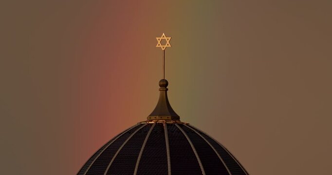Star of David on synagogue dome top with rainbow in sky and bird flying past extreme telephoto close up slow motion