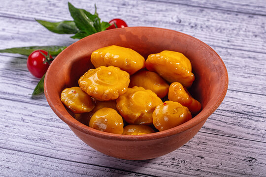 Pickled yellow patisson squash in rustic clay bowl on wooden background