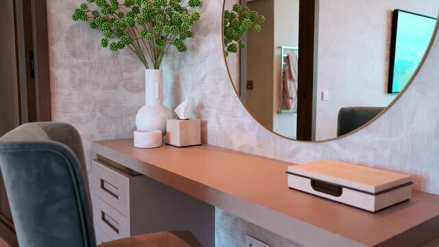 Elegant and modern bedroom interior featuring a stylish vanity with a round mirror, comfortable velvet chair, and decorative elements, showcasing a luxurious and comfortable living space