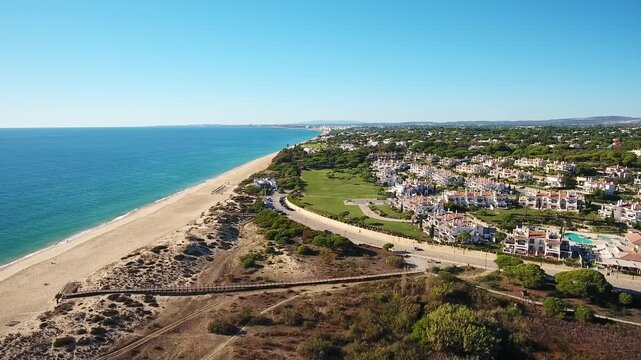 Aerial drone view of vale do lobo and praia de garrao coastline in the algarve, portugal, showing sandy dunes, blue atlantic waters, luxury beachfront villas and resort landscape