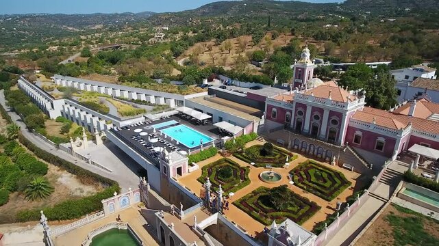Pousada palacio de estoi in the algarve region of portugal, featuring its magnificent rococo palace, beautiful formal gardens, and modern luxury hotel with a swimming pool on a sunny day