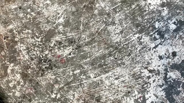Weathered concrete surface with distressed white markings, scratches, stains, and rugged industrial patterns, creating a grunge texture background for urban and abstract designs.