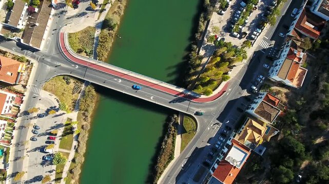 Aerial top down view showing cars driving over a modern bridge spanning the gilao river in the historic town of tavira, located in the algarve region of southern portugal