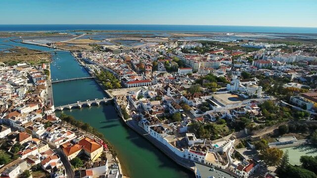 Beautiful panoramic aerial shot of the historical town of tavira in the algarve region of portugal, showing the gilao river, the ancient roman bridge, and the atlantic ocean in the background
