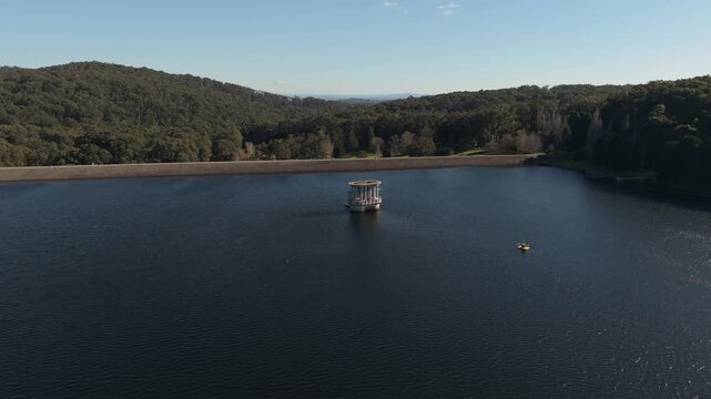 Silvan, Australia - 01 September 2026: Aerial view of Silvan Reservoir Park with its central valve tower surrounded by calm water and dense forest.
