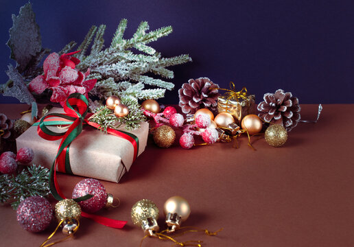 Christmas scene with handmade craft gift box with bow, decorative fir branch, balls and cones for tree decoraton. New Year winter holiday composition with presents, ornaments and decor.