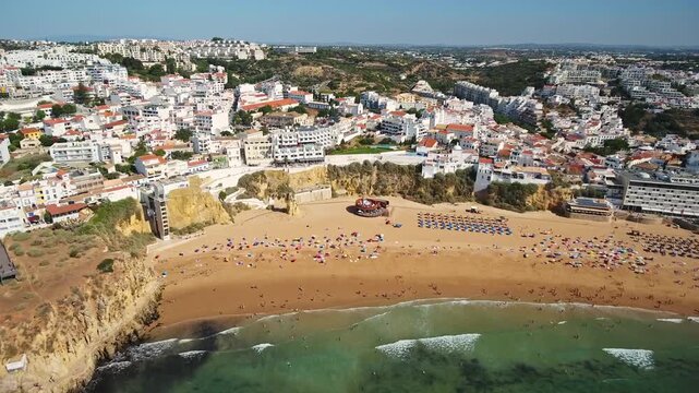 Stunning aerial view of praia dos pescadores in albufeira, golden sand, turquoise atlantic waves and whitewashed old town perched on the sunlit algarve coastline