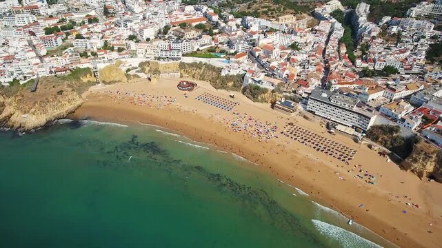 Spectacular high angle aerial view of the praia dos pescadores, or fishermen's beach, with tourists relaxing on the sand next to the beautiful old town of albufeira in algarve, portugal