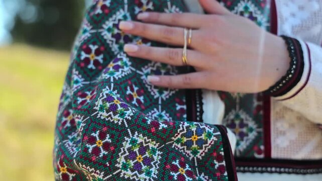 Close view of a colorful embroidered bag held by a woman in folk clothing, Embroidered clothing represents folk culture design and artisan tradition