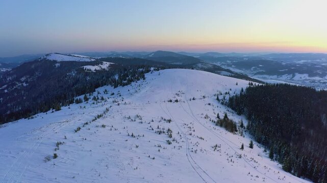 An extraordinary valley with hills and mountains covered with fir forests against the backdrop of a bright pink sunset