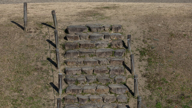 Old stone stairs with rustic wooden posts on grassy slope outdoors in Japan suitable for travel and background design