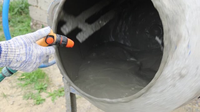 Mixing concrete in a drum with a hose in the yard