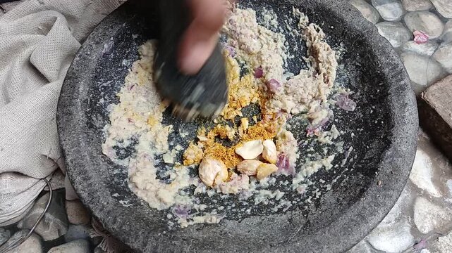 Crushing Spices and Candlenuts in Stone Mortar and Pestle for Asian Cooking