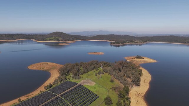 Christmas Hills, Australia - 31 August 2026: Aerial view of Sugarloaf Reservoir with a solar farm on the shore, surrounded by hills and native trees.