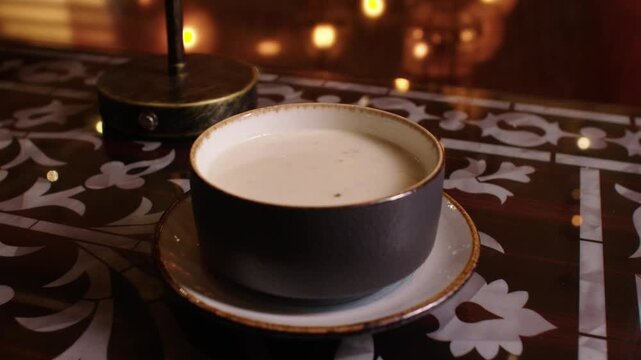 Steaming cup of salep, a traditional Turkish hot milk beverage, resting on a fancy table