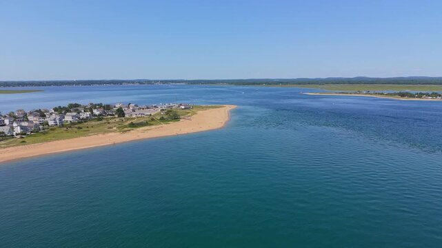 Forward drone fly toward curved sandy Plum Island Beach endpoint with coastal residential community and calm blue waterway inlet entrance, Massachusetts, United States