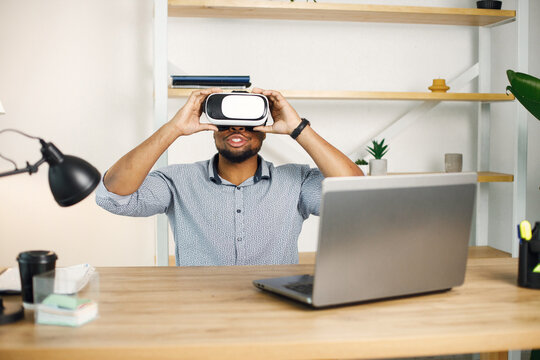 Black male entrepreneur sitting in office and using virtual reality glasses