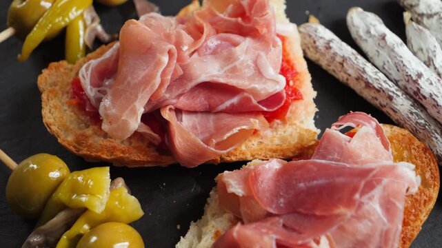 Pan con tomate topped with slices of jamon, Gilda Pintxo and mini fuet sausages. High quality 4k footage