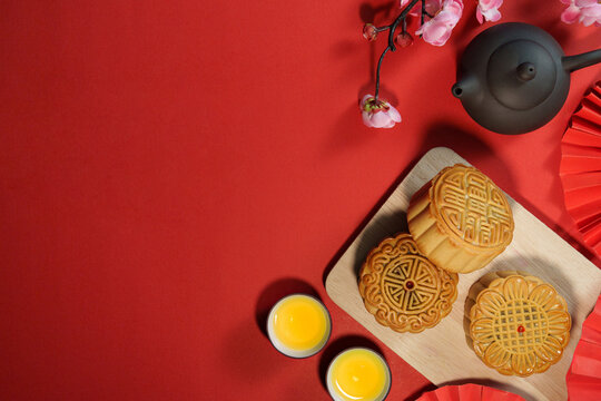 Chinese mooncakes with teapot and tea cups on red background for Mid Autumn Festival