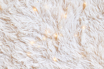 Light white fur background with christmas light. Cozy fluffy fabric textile texture with soft wavy faux fur material © Caterina Trimarchi