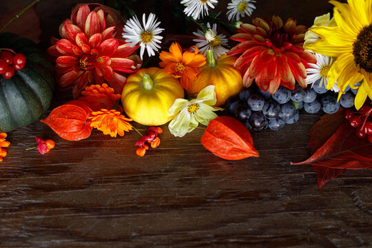 Happy Thanksgiving. Pumpkins, autumn leaves, berries and flowers border on old wooden table with copy space. Atmospheric fall flat lay. Fall season banner