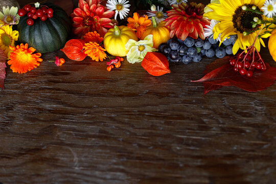 Autumn flat lay. Colorful pumpkins, autumn leaves, flowers border on rustic wooden table. Happy Thanksgiving. Fall season greeting card, space for text