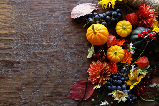 Autumn flat lay. Colorful pumpkins, autumn leaves, flowers border on rustic wooden table. Happy Thanksgiving. Fall season greeting card, space for text