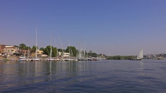 View of traditional felucca boats moored along the banks of the Nile River in Aswan, Aswan Governorate, Egypt.
