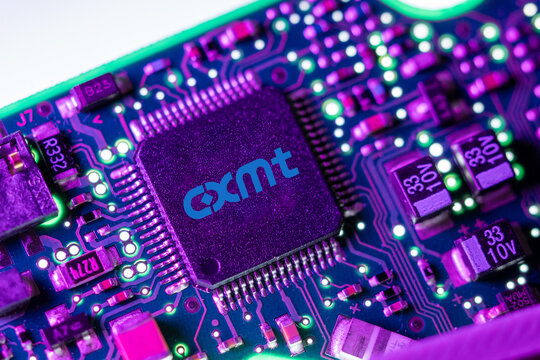 Macro shot of a CXMT semiconductor chip on a circuit board with neon lighting.