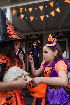 Cute little children joyfully dressed in Halloween costumes enjoying trick or treat fun