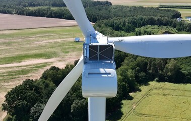 Aerial view of the nacelle and rotor blades of a wind turbine in a countryside landscape © harhar38