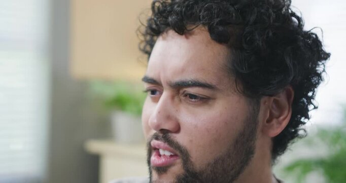 Adult African American man speaking and reacting after question in living room with potted plant