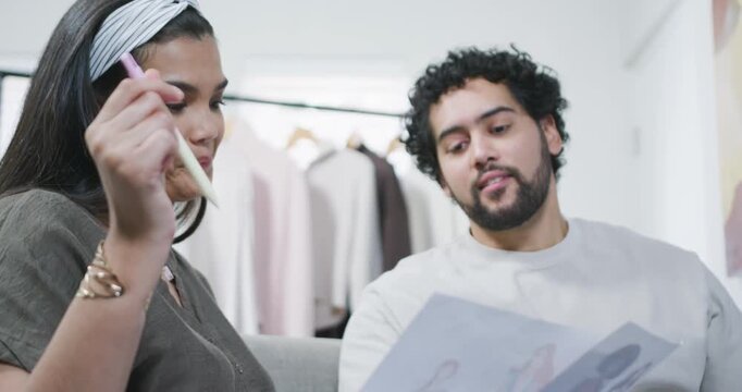 African American couple, woman raising pen and pointing through pages on sofa, choosing outfits