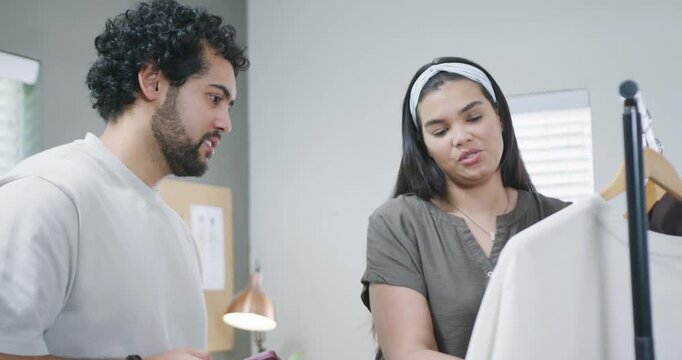 African American coworkers lifting shirt from rack, inspecting buttons while checking smartphone