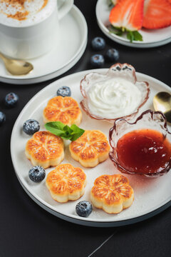 Cottage cheese pancakes, syrniki, curd fritters decorated with strawberry and raspberry served on a white plate. Homemade breakfast concept