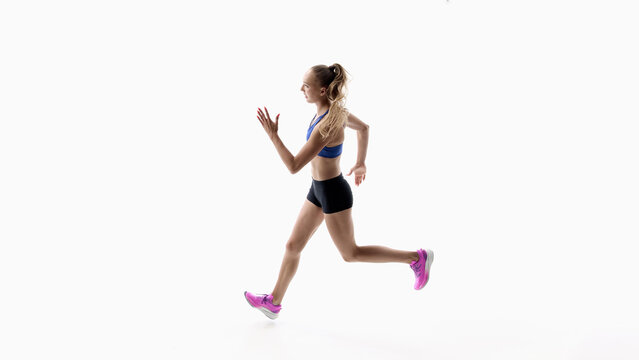 Side view female runner sprint capturing rapid movement on white studio background. Concept of race tempo, athletic mobility and dynamic cardiovascular exercise.