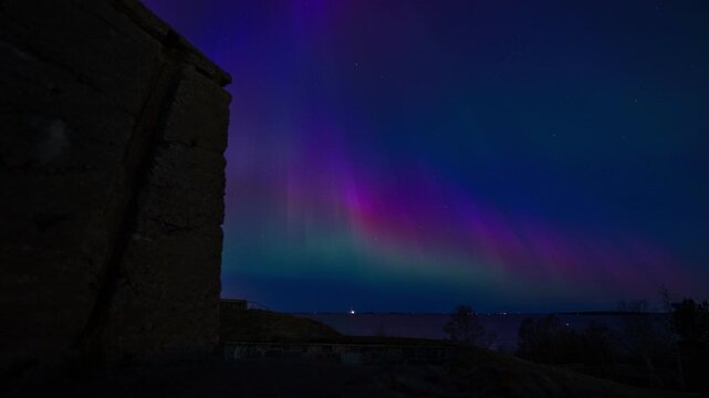 View of a vibrant purple and green aurora borealis timelapse over the historic stone walls of Suomenlinna in Helsinki, Uusimaa, Finland. Timelapse.