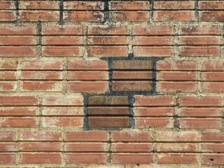 Weathered brick wall texture with red bricks and mortar creating a pattern © Harry