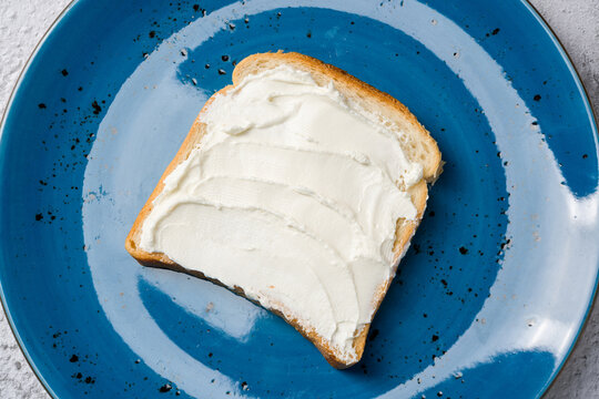 Slice of bread with cream cheese on a blue plate
