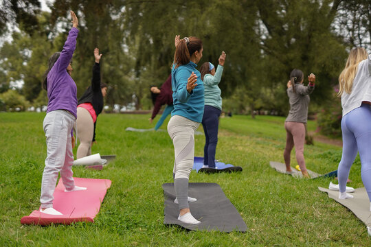 Group of women with different body and ethnic doing yoga exercise at city park - Multiracial female community, healthy lifestyle and diverse people concept