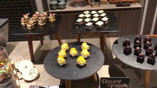 Assortment of delicious bite sized French pastries displayed on slate serving platters at a buffet.