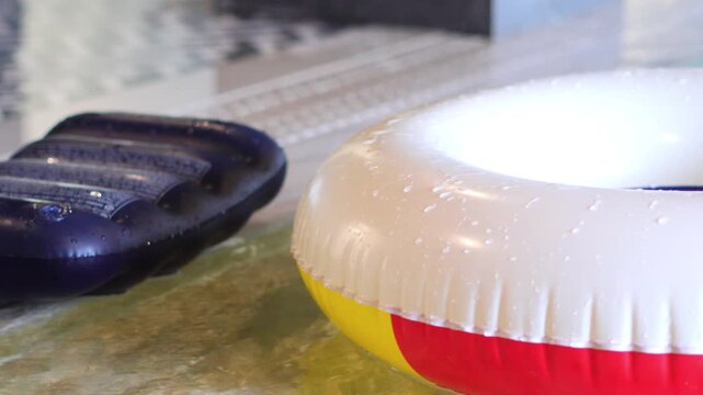 Inflatable swim ring and mattress floating near the edge of a swimming pool.

