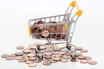 Mini shopping cart filled with coins on white background © PhamHong