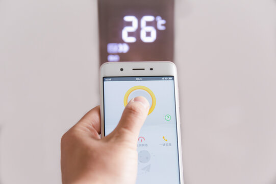 Smartphone controlling wall thermostat at 26 degrees in a smart home