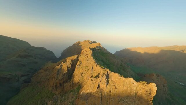 FPV aerial view of the rugged mountain ridge in Tenerife during golden hour with dramatic shadows and rocky terrain in Santa Cruz de Tenerife, Canary Islands, Spain.