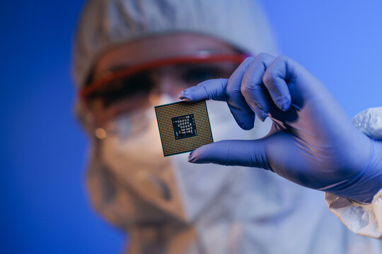 Laboratory technician holding microchip in cleanroom environment, concept control quality of semiconductor on lab of artificial intelligence factory